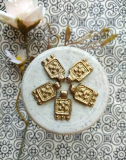 Antique Brass Charms – Close-up view of a vintage brass charm with intricate patina details.