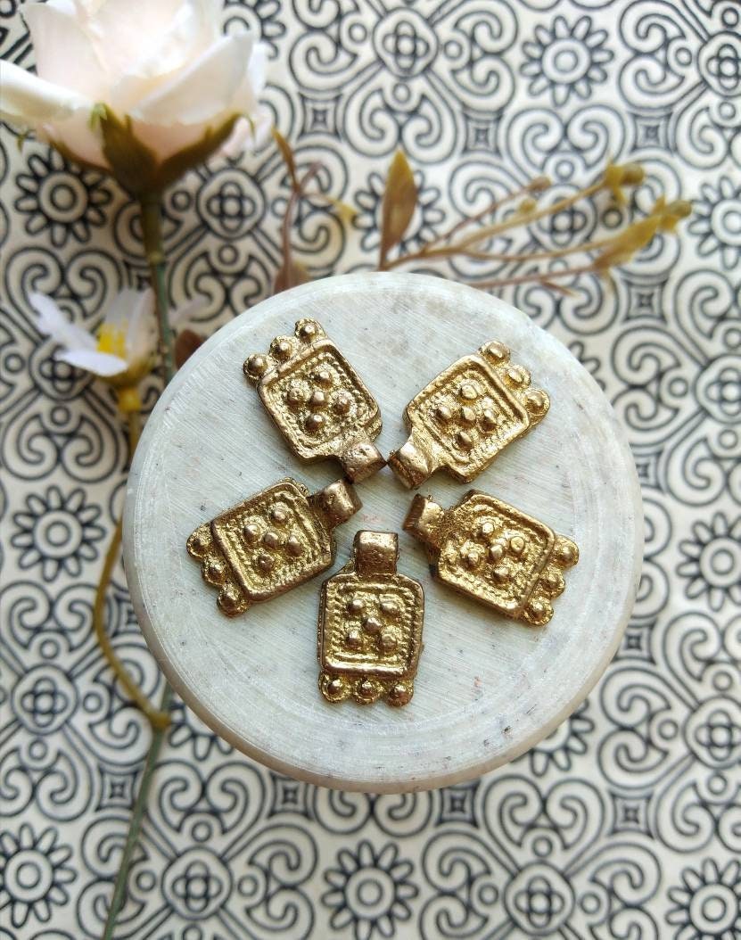 Antique Brass Charms – Close-up view of a vintage brass charm with intricate patina details.