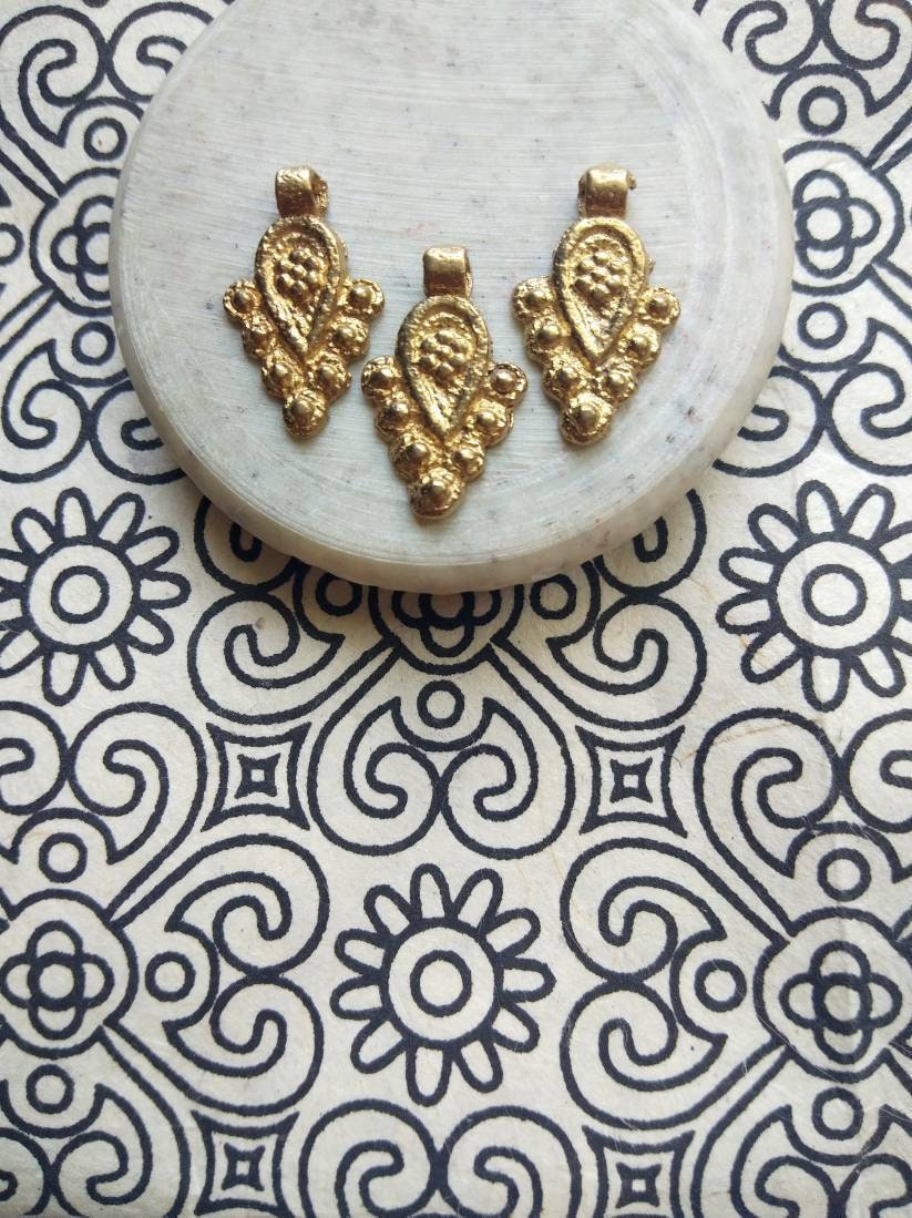 brass jewelry charms – Shop now: Close-up of artisan-crafted charms with intricate detailing.